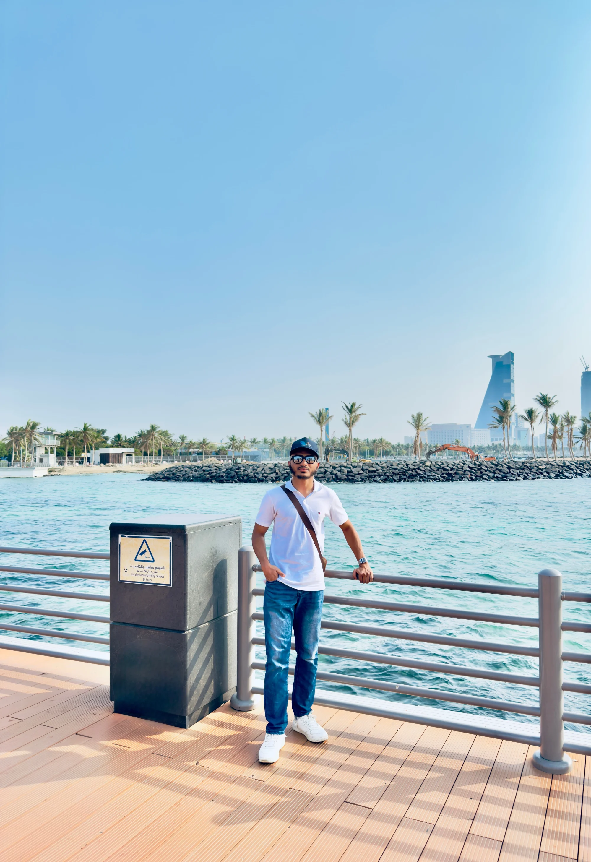 Standing at a railing on the corniche above green water