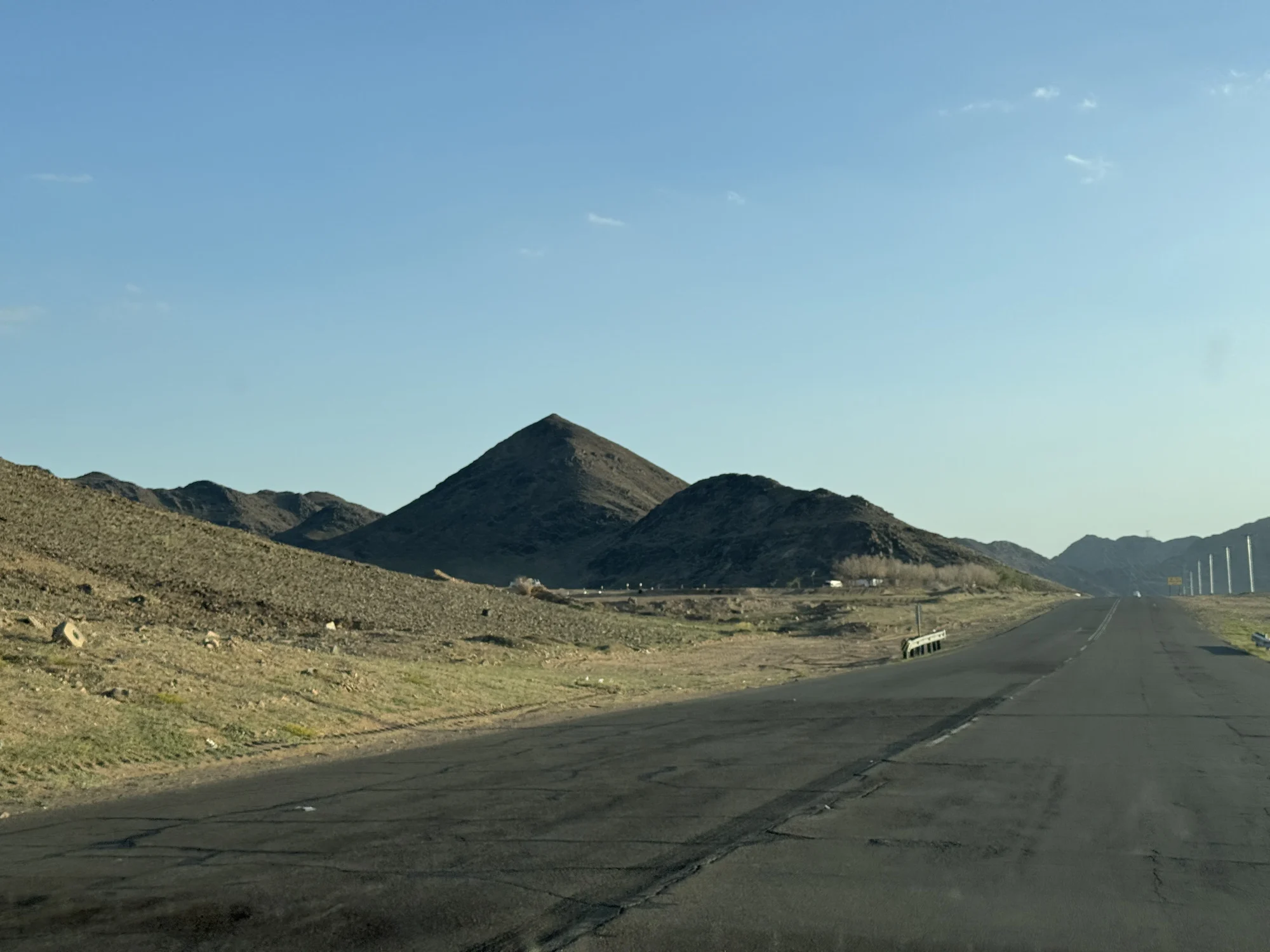An empty road running out towards a dark peak