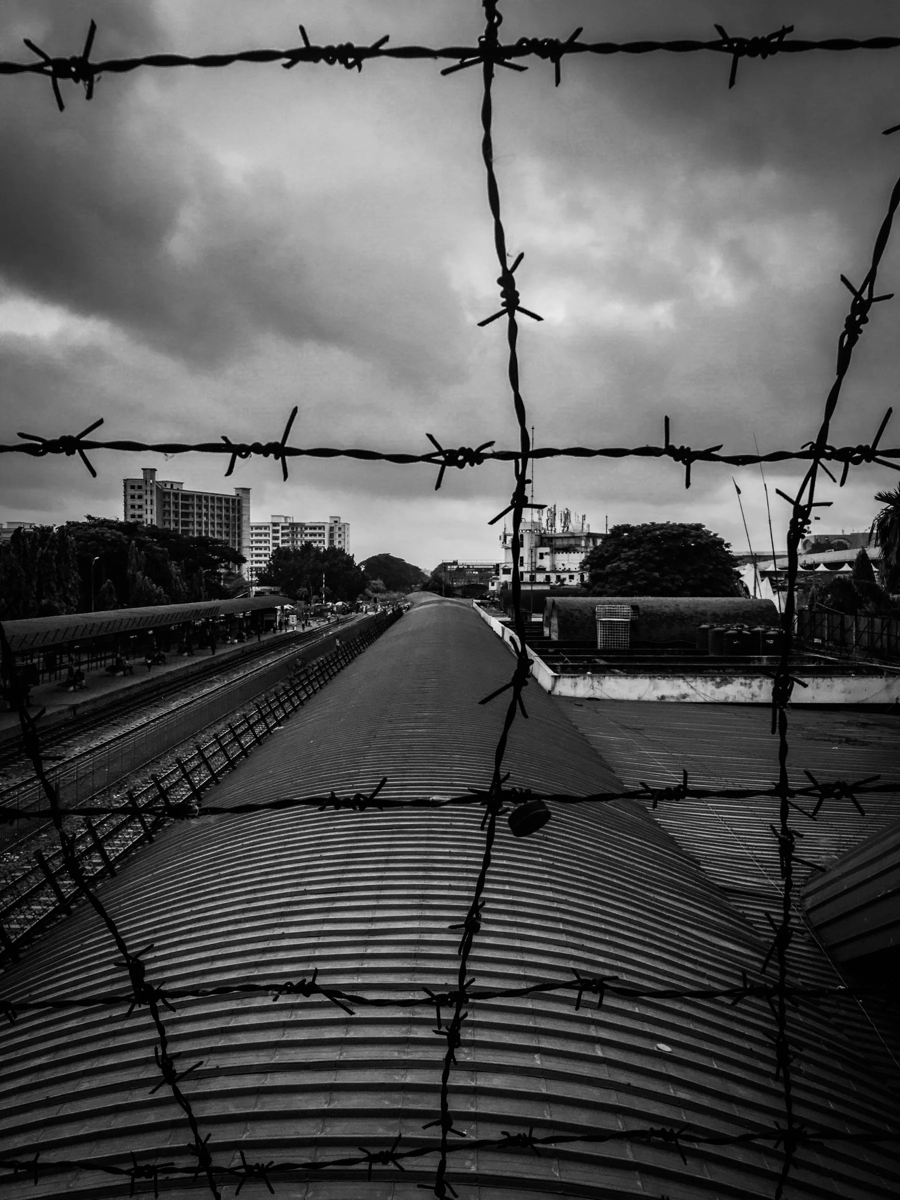 Station roofs and city buildings seen through strands of barbed wire