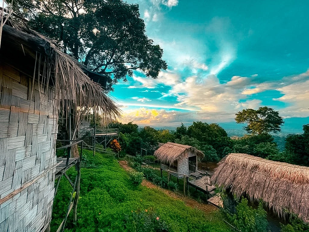 Bamboo huts stepping down a green hillside toward the lowland