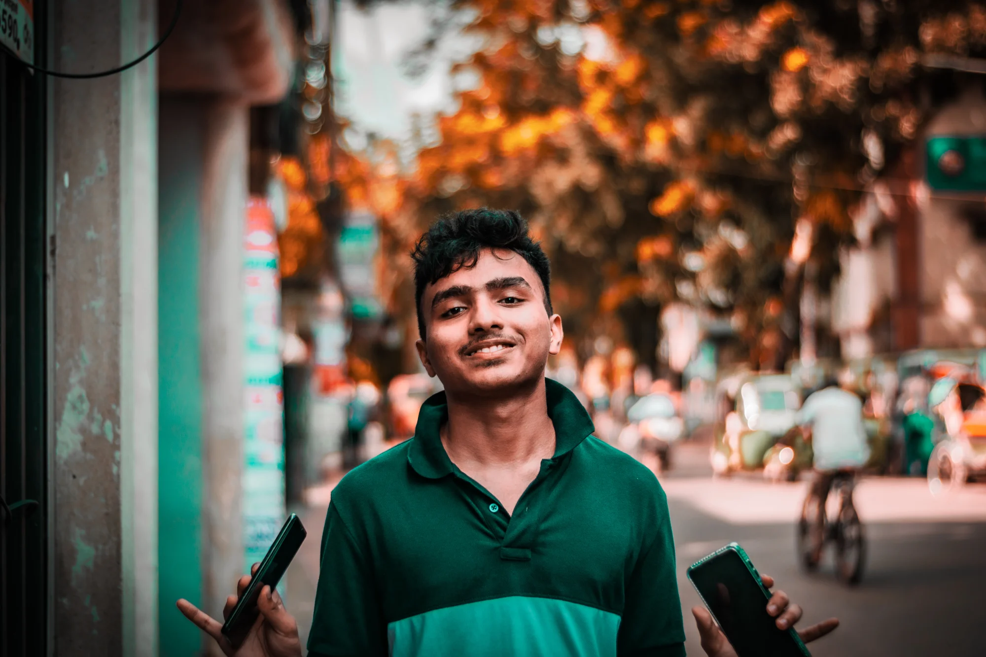 Faiyaj on a street at golden hour, a phone in each hand