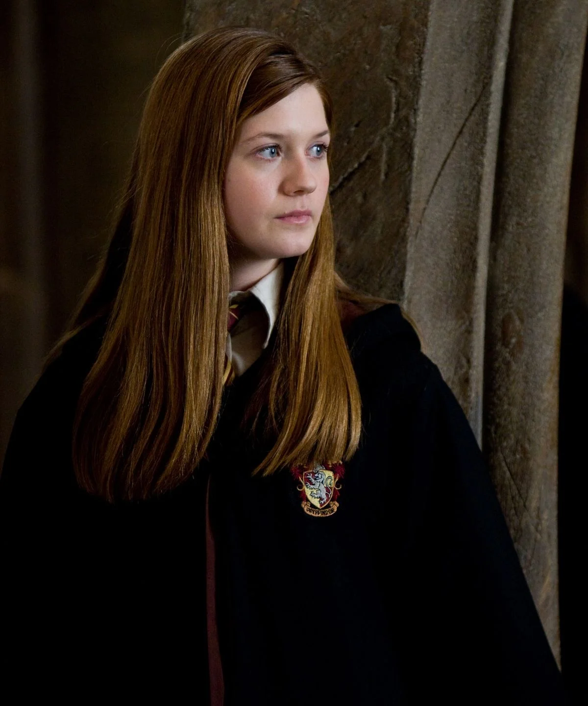 Ginny Weasley against a stone pillar