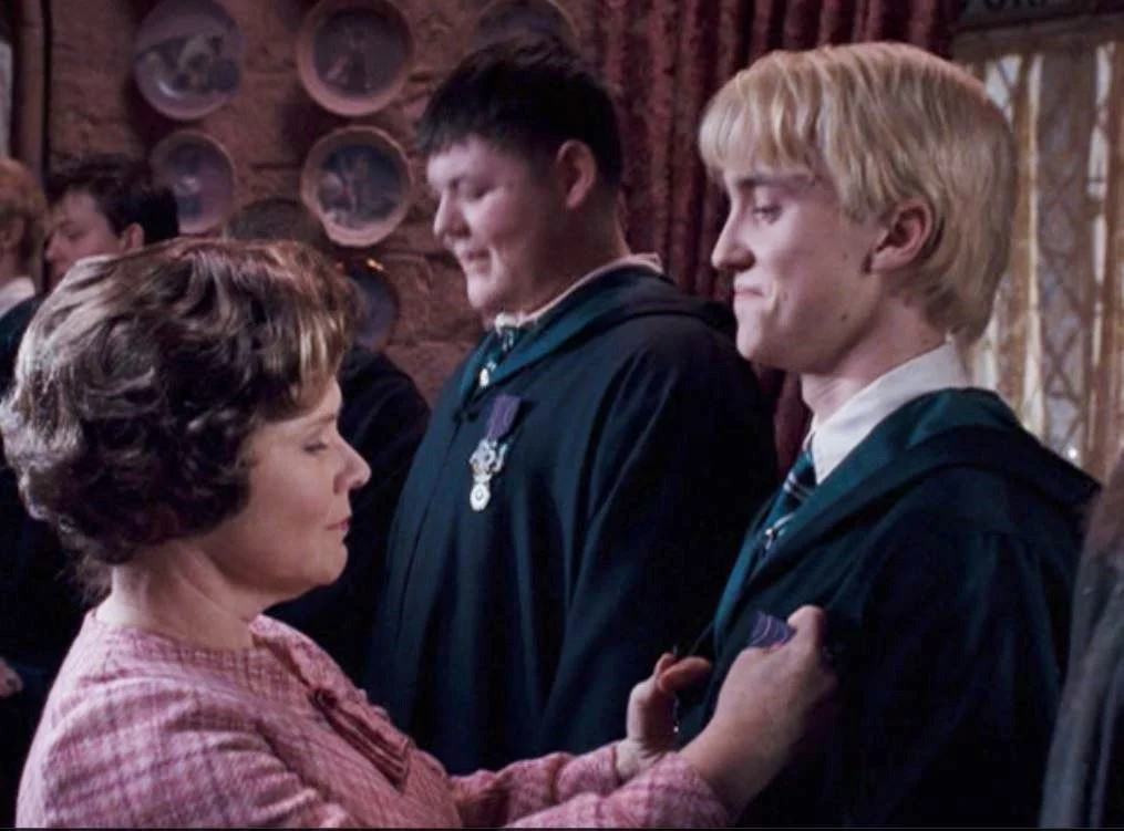 Umbridge pinning a badge on Draco Malfoy