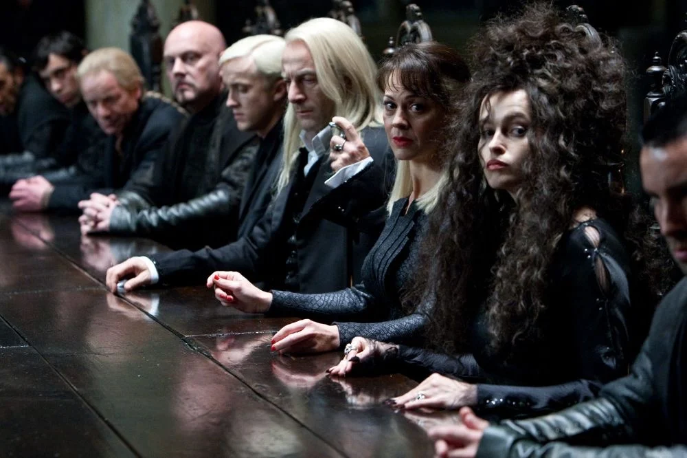 Death Eaters seated along a long dark table