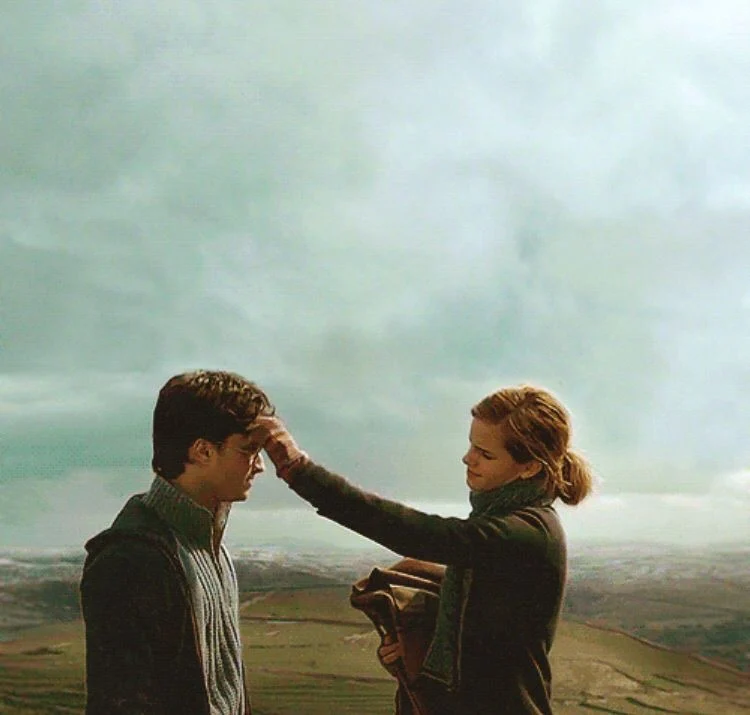 Hermione touching Harry's forehead on a hillside