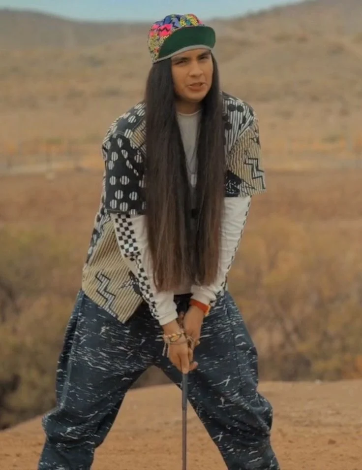 Argyle standing in the desert holding a golf club