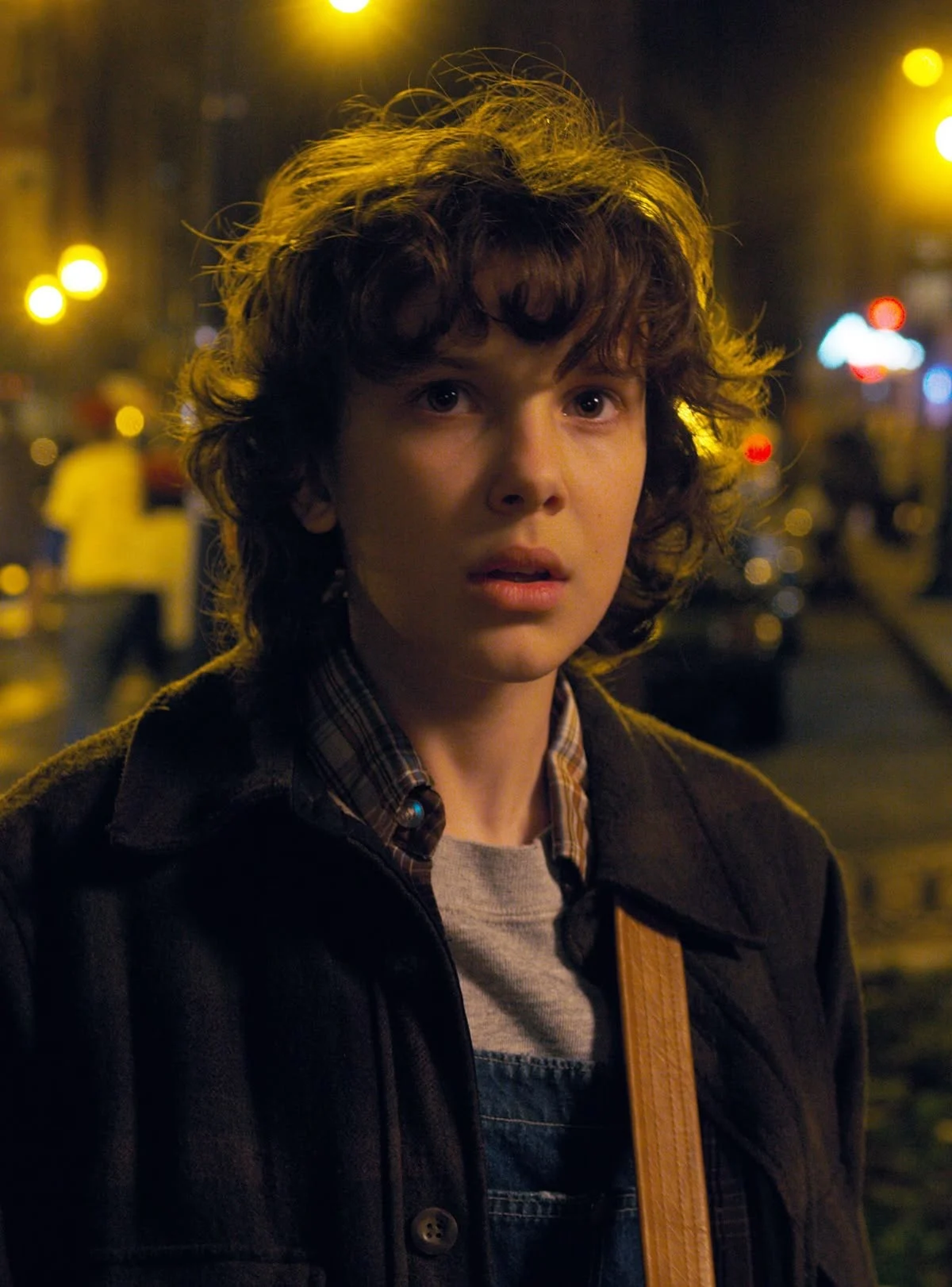 Eleven with curled hair on a city street at night