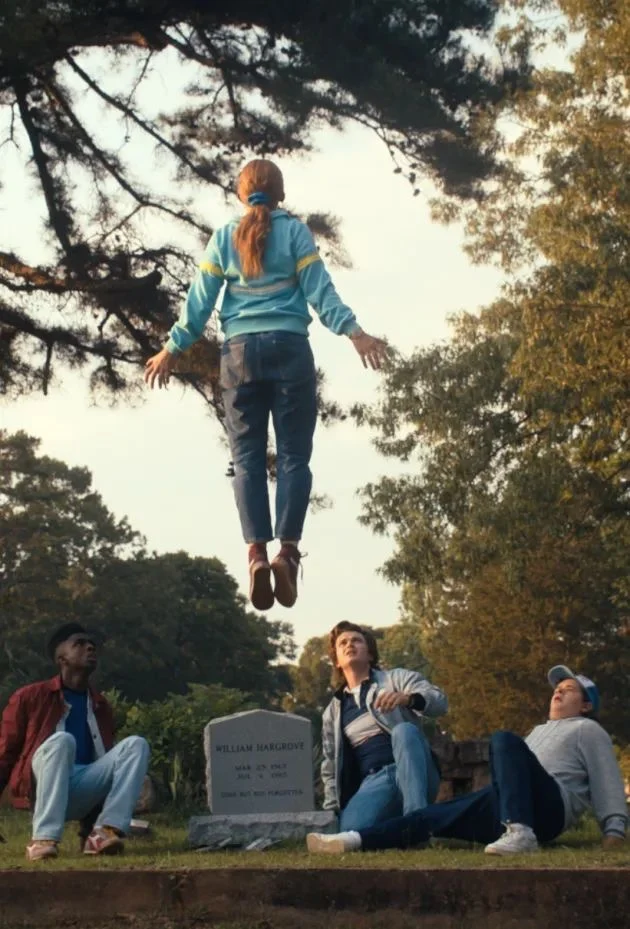 Max lifted into the air above a headstone while three friends sit below