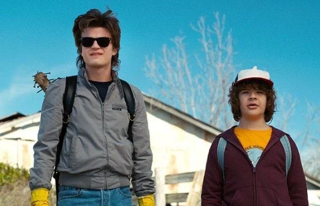 Steve in sunglasses and Dustin walking along a road